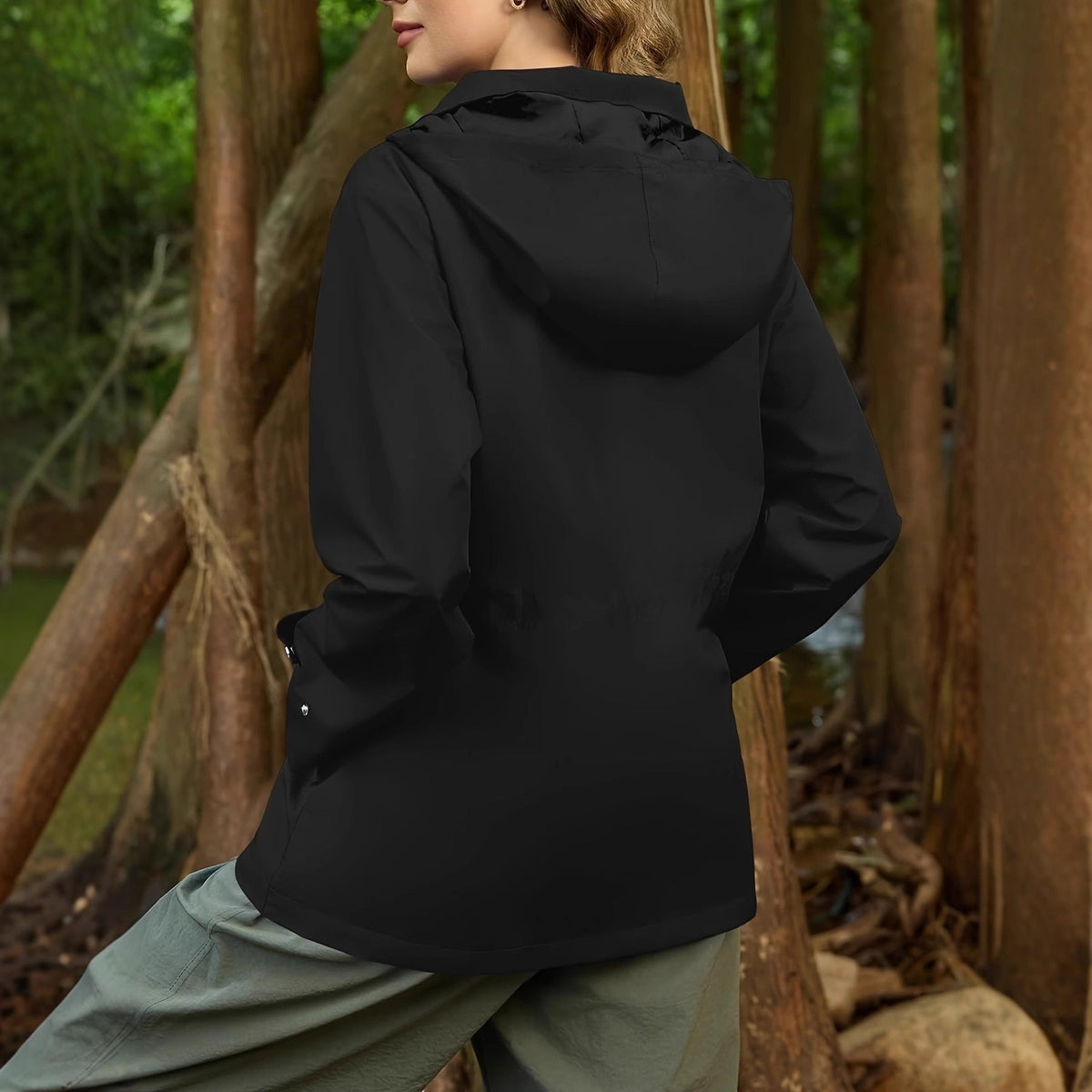 Achterkant van de zwarte regenjas met de capuchon op, buiten | Boutique Moda