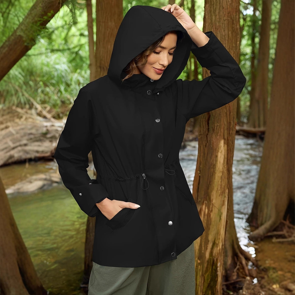 Zwarte regenjas met de capuchon op, in het bos | Boutique Moda