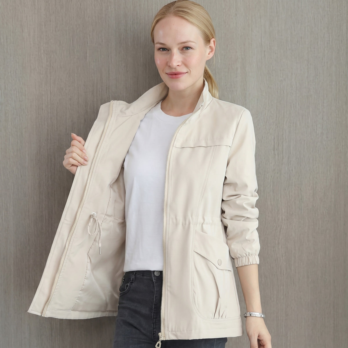 Vrouw in de lichte regenjas in steenbeige met opstaande kraag | Boutique Moda
