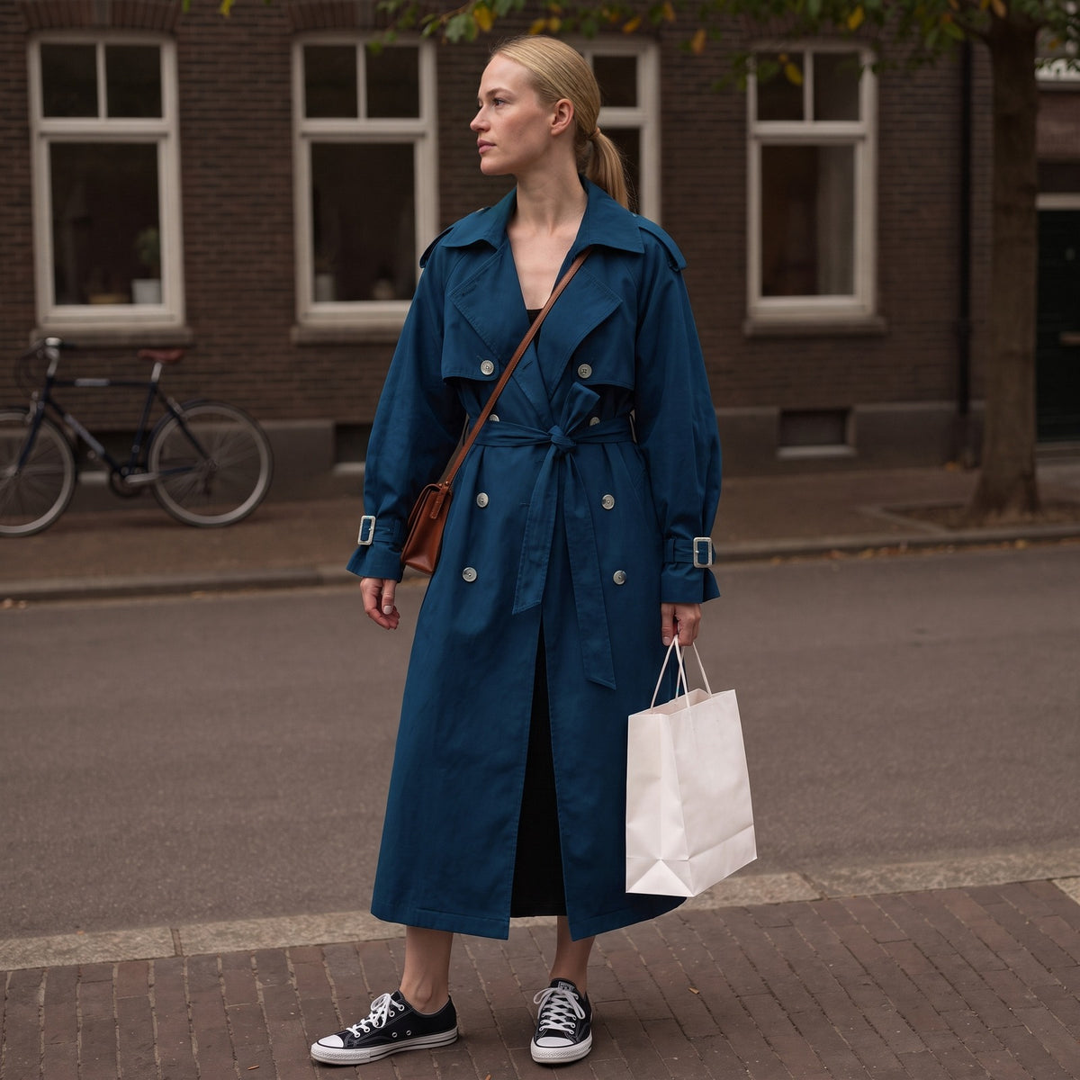 Lange trenchcoat in marineblauw met ceintuur, buiten gedragen | Boutique Moda