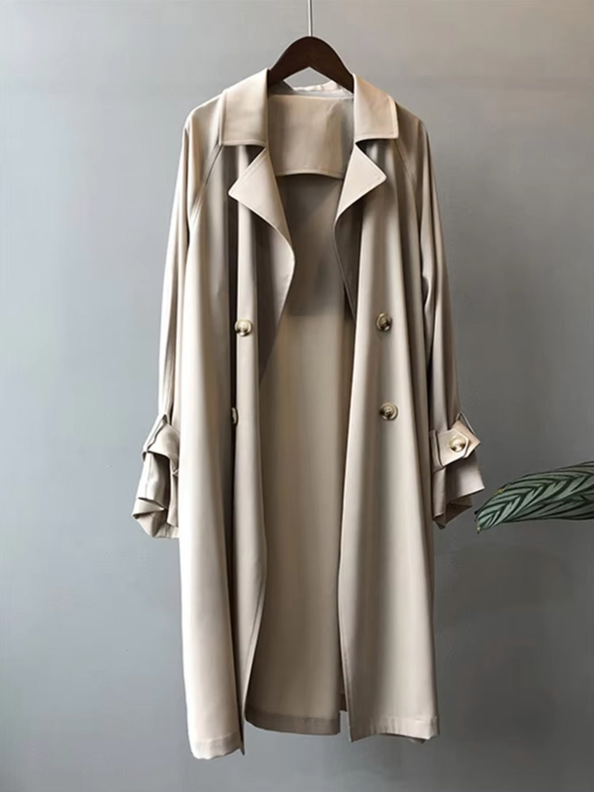 Lange trenchcoat met dubbele knopenrij in beige aan een hanger | Boutique Moda