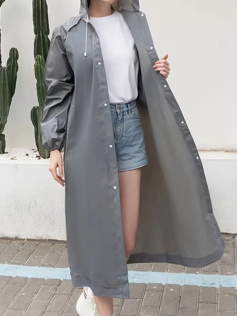 Lange grijze regenjas met capuchon, open over een wit T-shirt en korte spijkerbroek | Boutique Moda