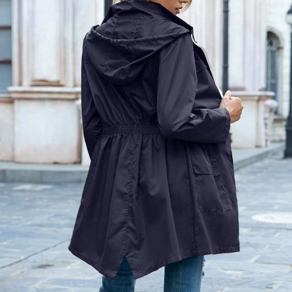 Achterkant van de marineblauwe regenjas met capuchon op en ingehaalde taille | Boutique Moda