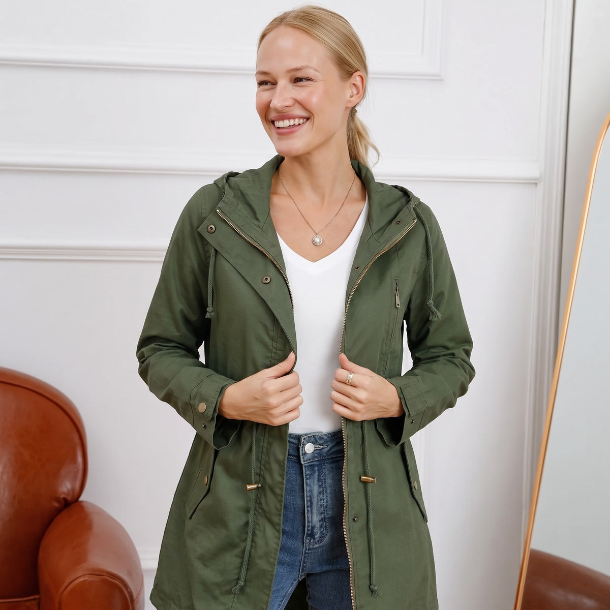 Olijfgroene parka met capuchon, open gedragen over een witte top en spijkerbroek | Boutique Moda