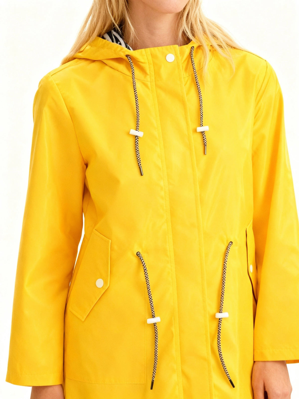 Close-up van de gele regenjas: trekkoorden, drukknopen en een zak met klep | Boutique Moda