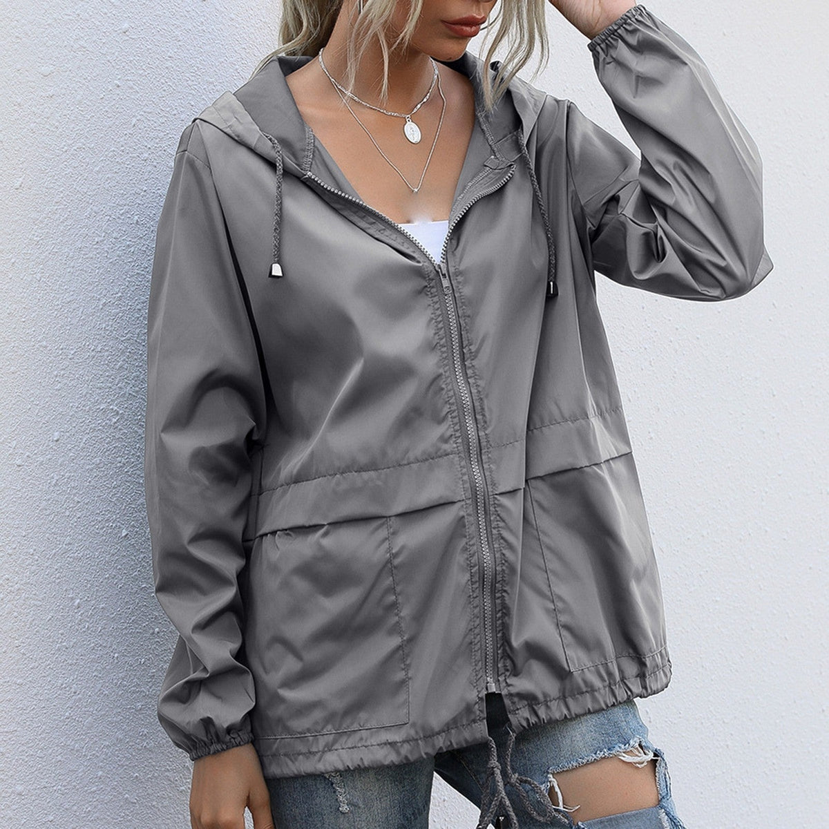 Grijze lichte waterdichte regenjas met capuchon en koord aan de zoom | Boutique Moda