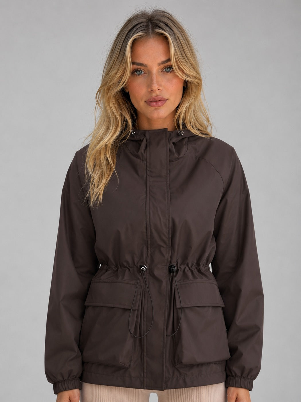 Bruine korte regenjas met capuchon, taillekoord en klepzakken | Boutique Moda