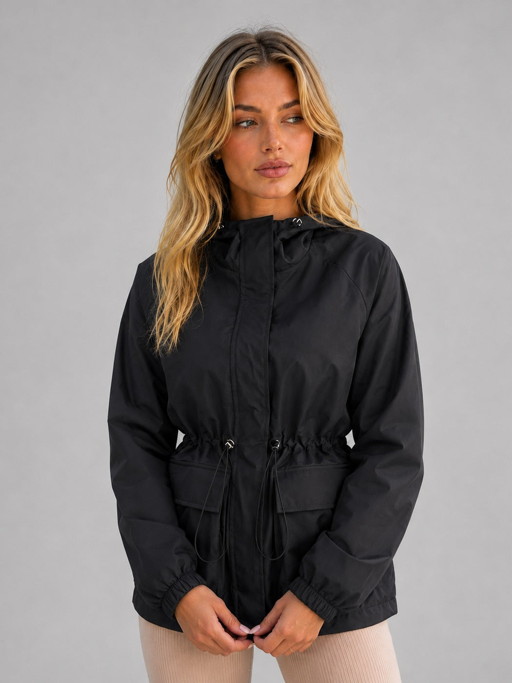 Zwarte korte regenjas met capuchon, taillekoord en klepzakken | Boutique Moda