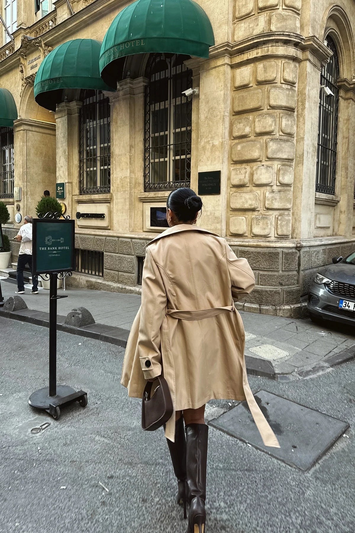 Achterkant van de beige trenchcoat met losjes hangende ceintuur | Boutique Moda
