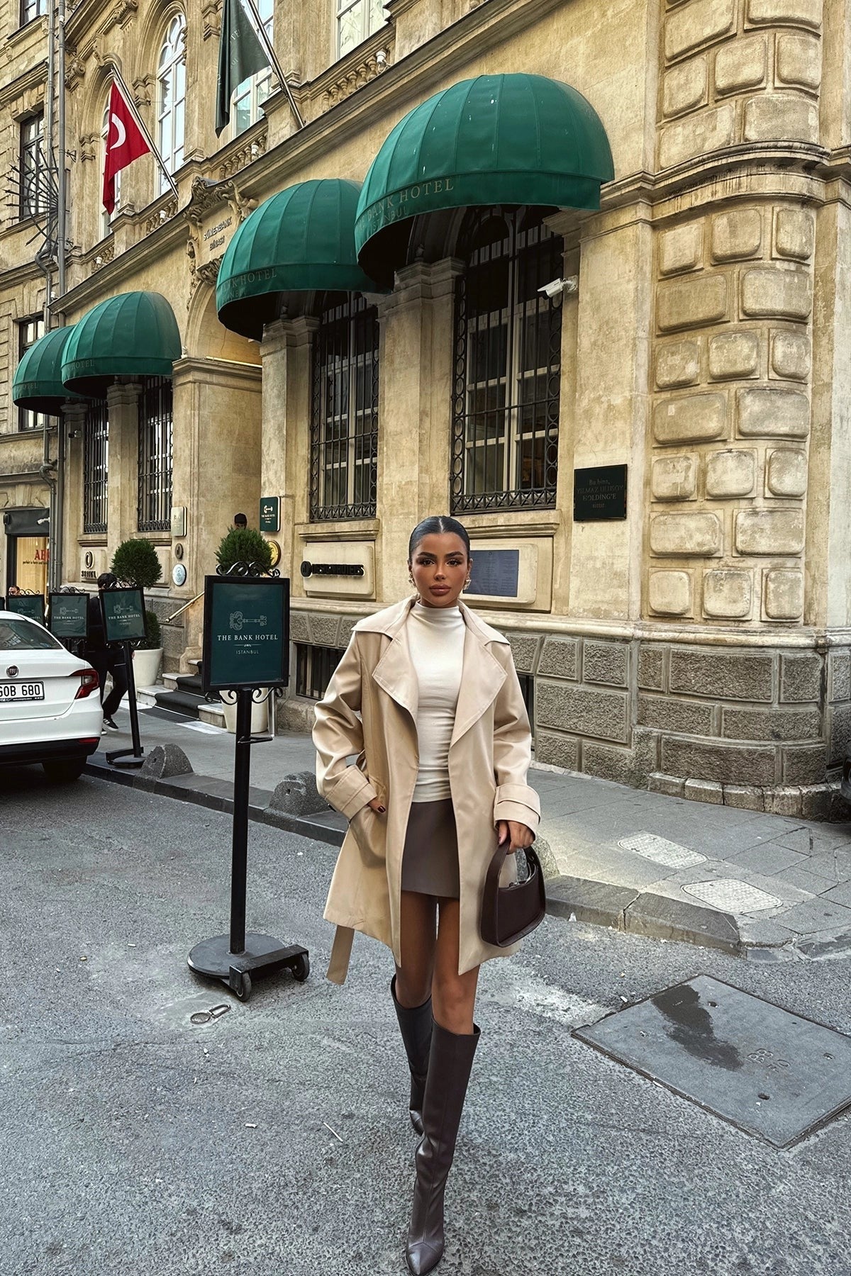 Beige trenchcoat open gedragen over een coltrui en een korte rok | Boutique Moda