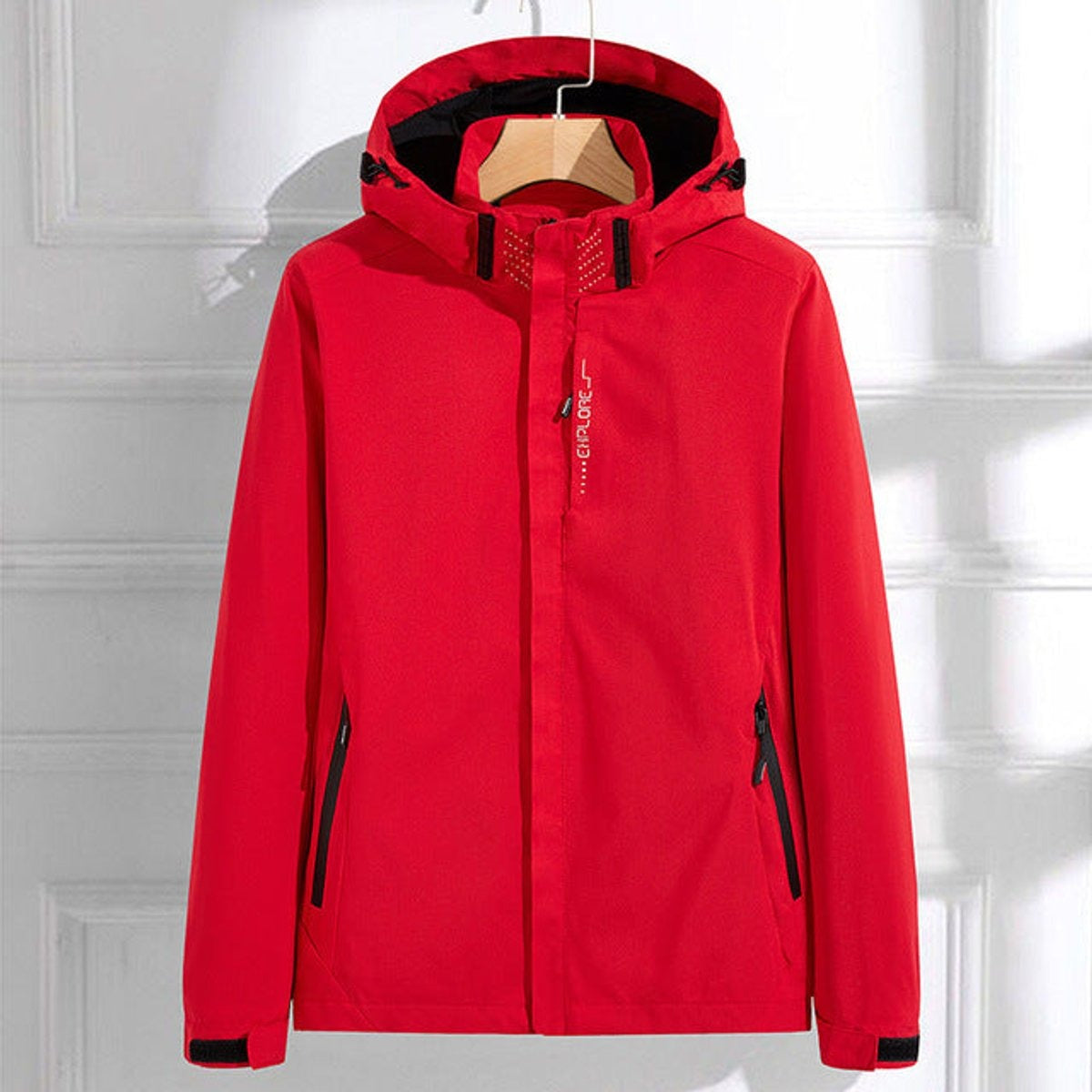 Rood waterdicht windjack met Explore-opdruk, capuchon en ritszakken met zwarte rand, aan een kledinghanger | Boutique Moda
