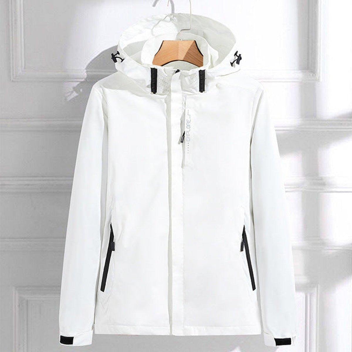 Wit waterdicht windjack met capuchon en ritszakken met zwarte rand, aan een kledinghanger | Boutique Moda