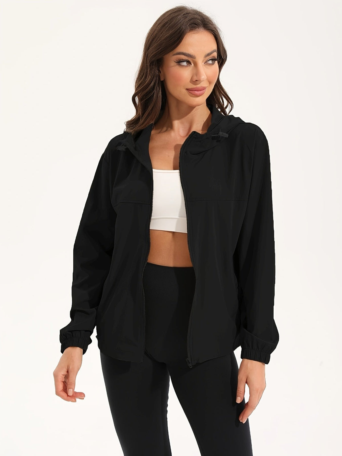 Zwart licht windjack met capuchon, open gedragen over een witte sporttop | Boutique Moda