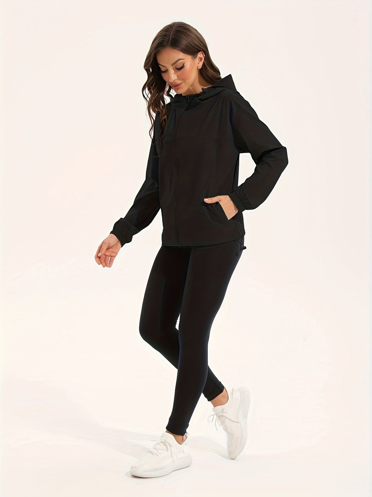 Zwart windjack dicht gedragen, lopend in legging en witte sneakers | Boutique Moda