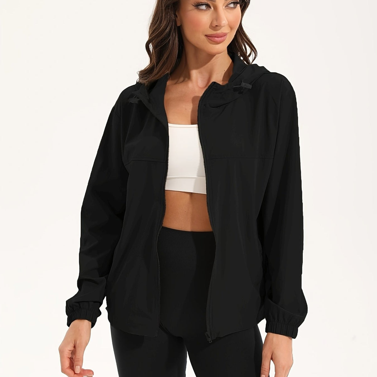 Zwart windjack met capuchon, open over een witte croptop | Boutique Moda