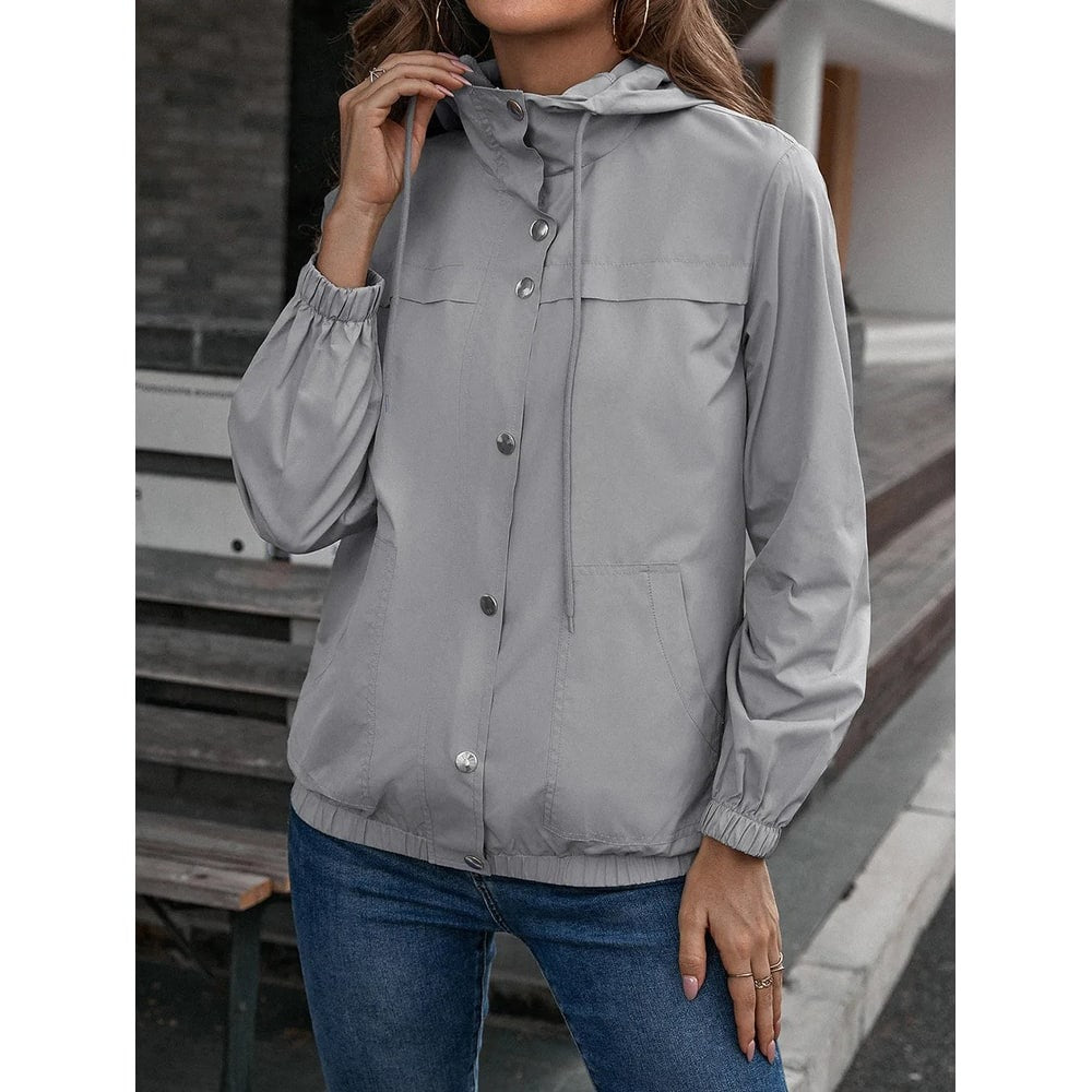 Grijs windjack met capuchon en zilveren drukknopen, gedragen met een spijkerbroek | Boutique Moda