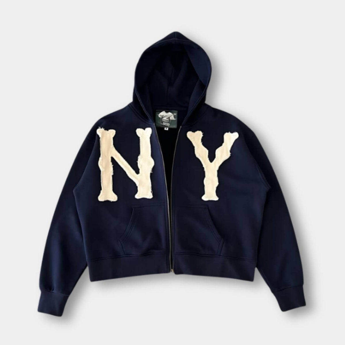 Marineblauwe oversized hoodie met rits en een crèmekleurige NY-applicatie, voorkant | Boutique Moda