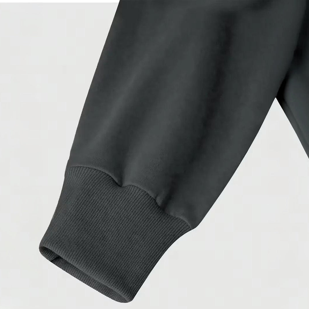 Close-up van donkergrijze mouw met geribbelde manchet, gedragen door een persoon | Boutique Moda