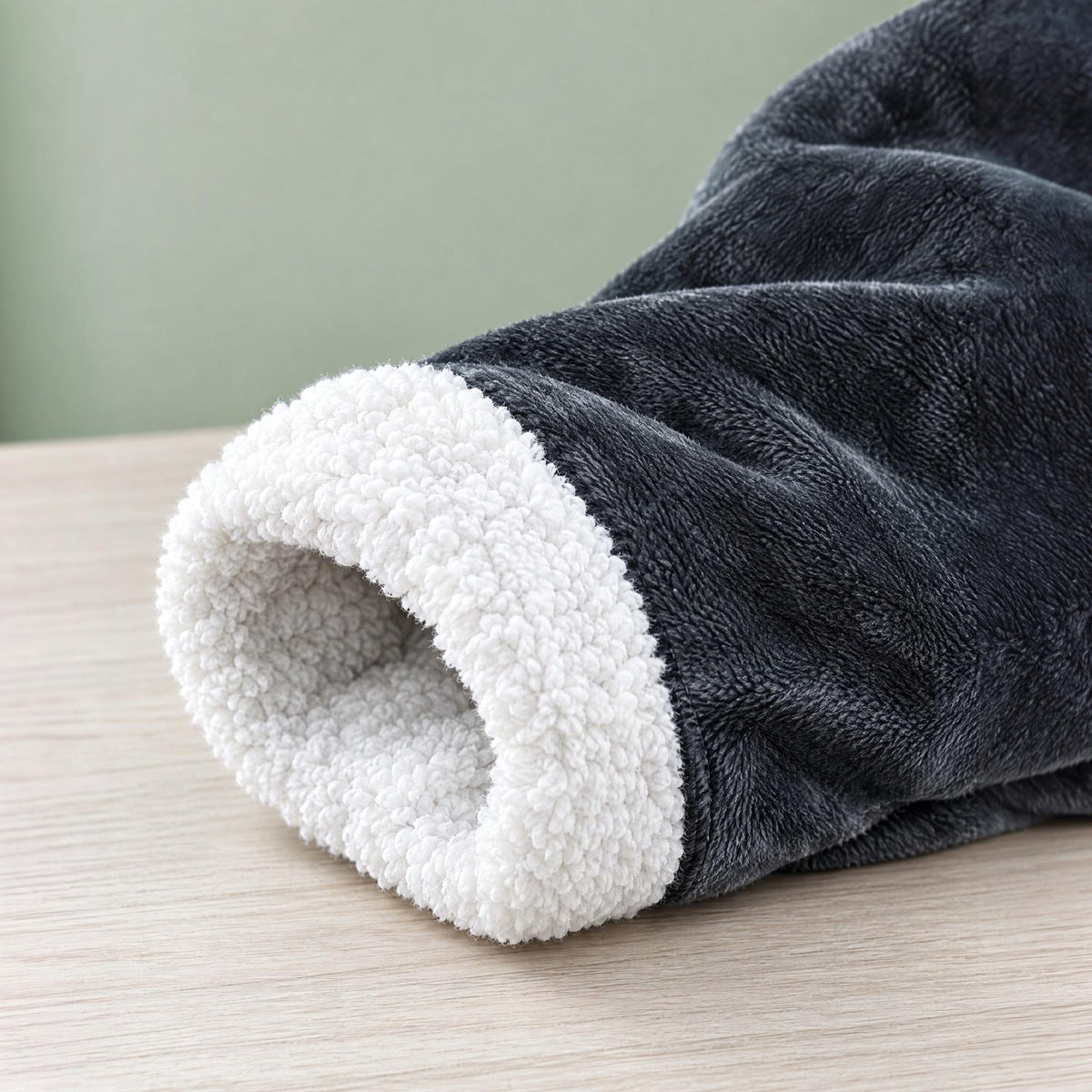 Donkergrijze mouw met witte sherpa voering, plat neergelegd op houten ondergrond | Boutique Moda
