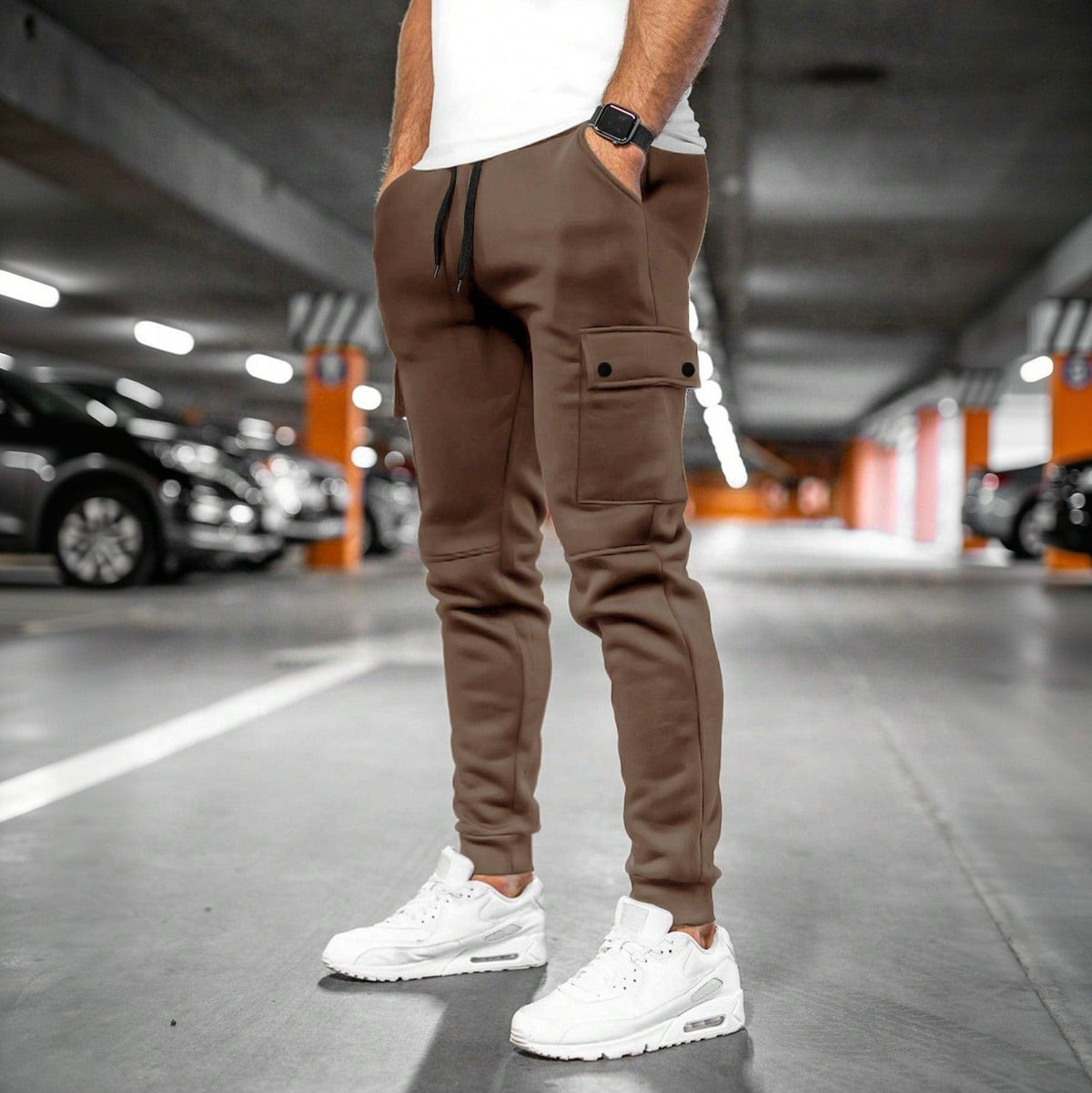 Bruine joggingbroek met cargozak, gedragen door man in parkeergarage | Boutique Moda