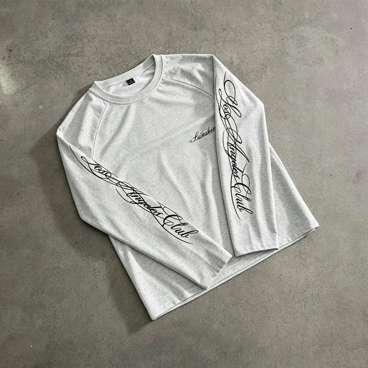 Grijze longsleeve met handschrift print op mouw, plat neergelegd | Boutique Moda