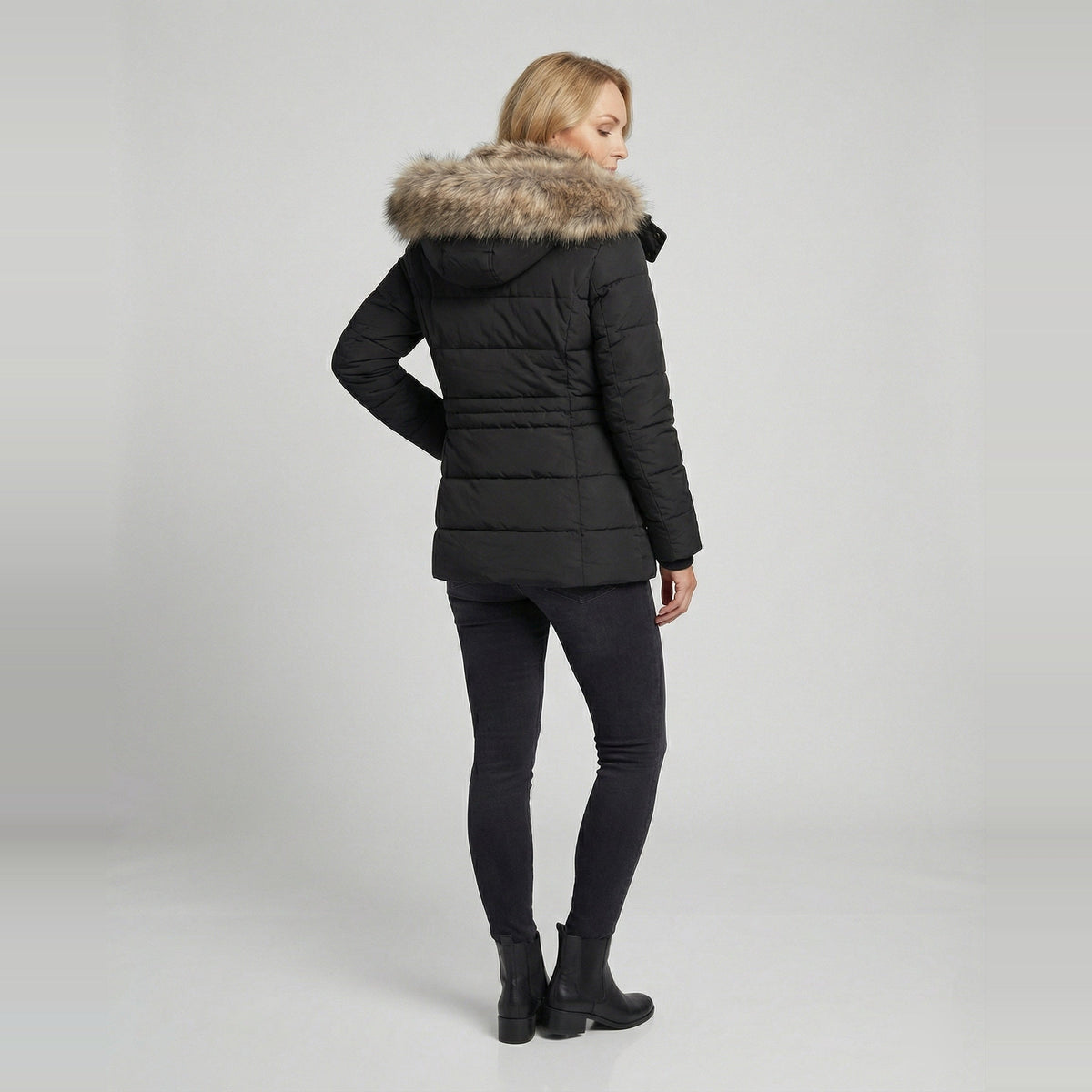 Zwarte winterparka met capuchon en imitatiebont, gedragen door vrouw achteraanzicht | Boutique Moda