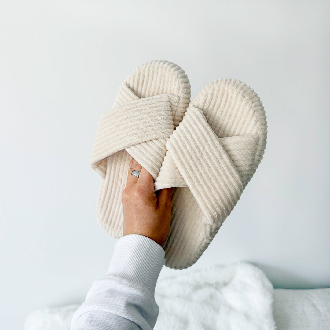 Beige ribfluwelen pantoffel met gekruiste banden in de hand