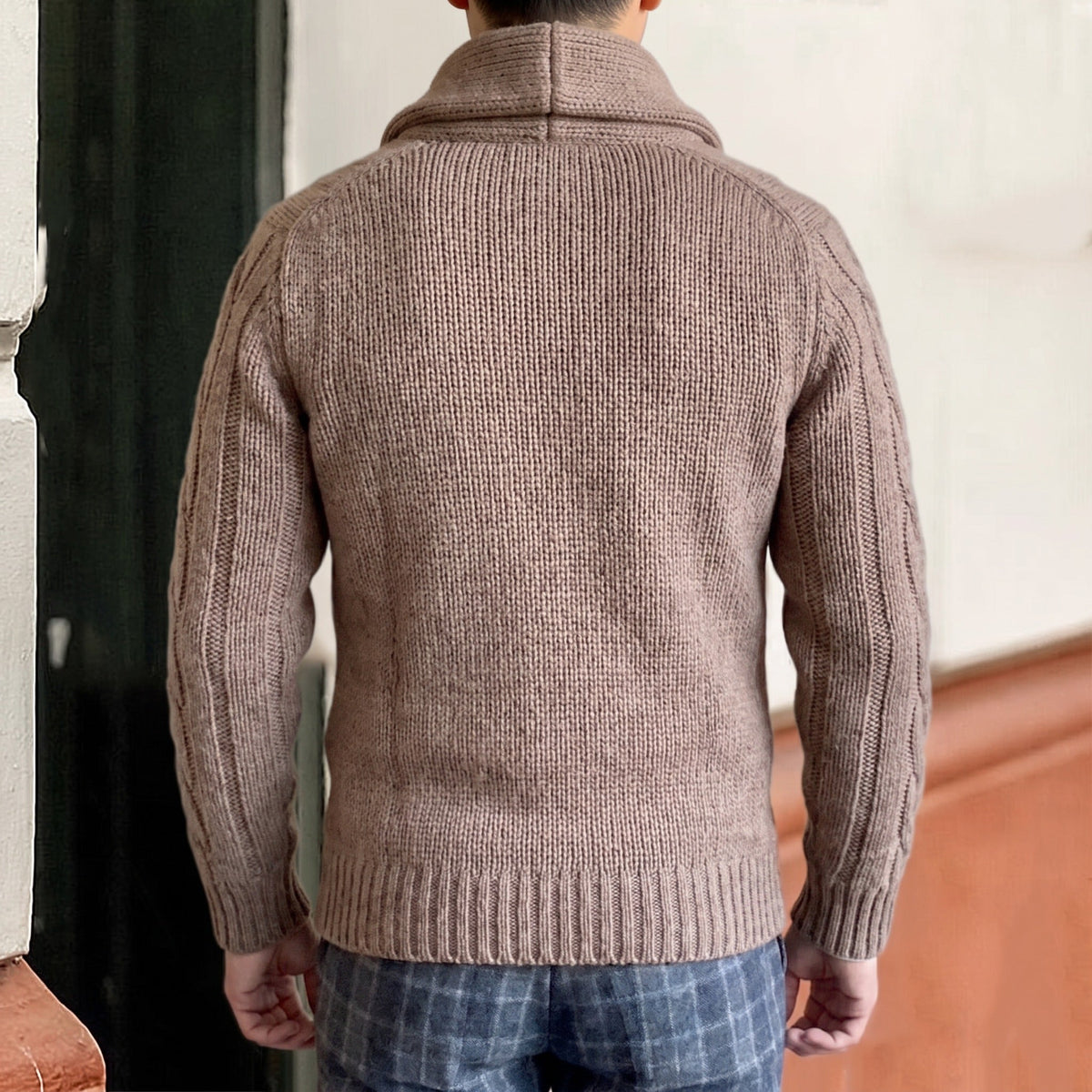 Man draagt beige gebreid vest met sjaalkraag, achteraanzicht met kabelpatroon | Boutique Moda
