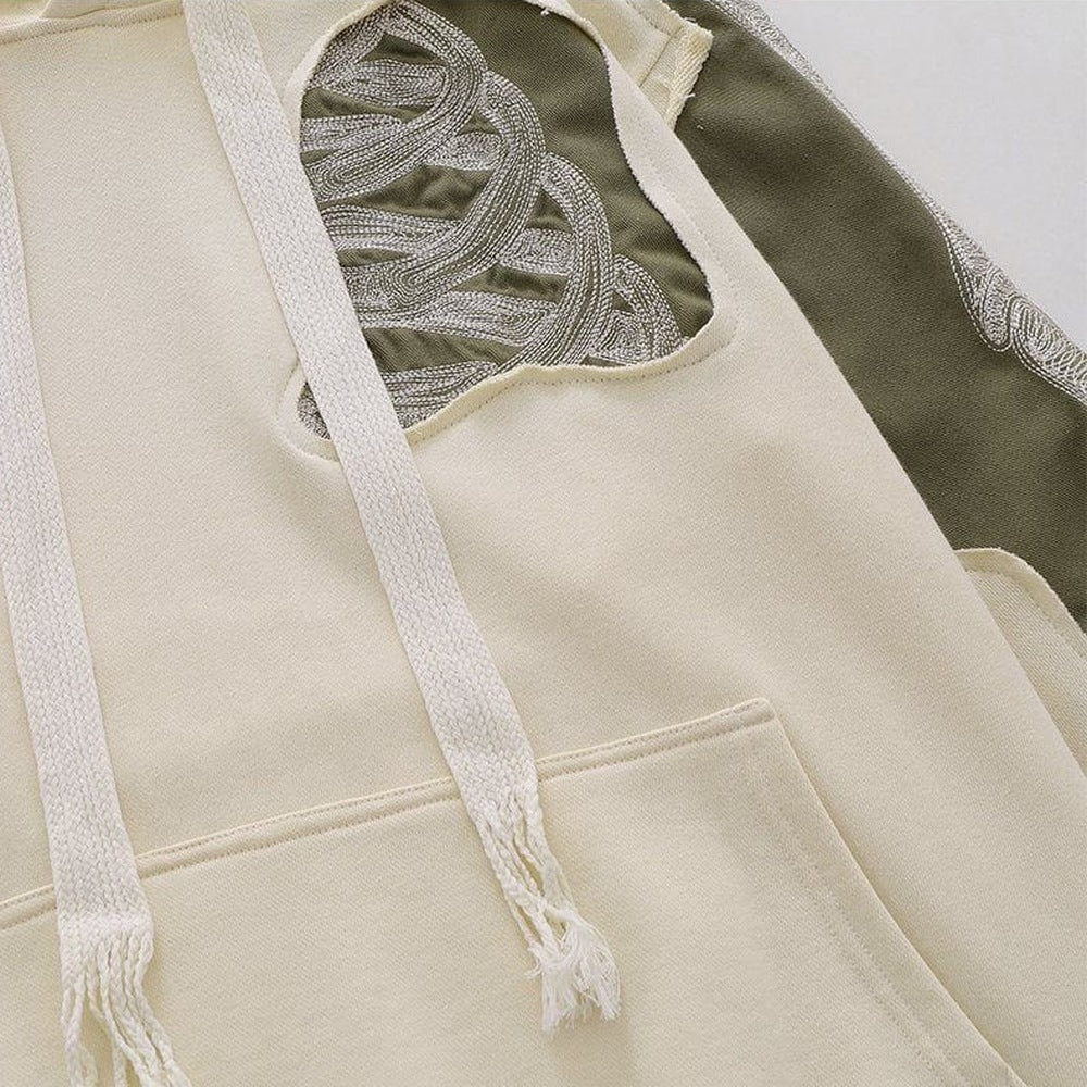 Close-up beige hoodie met geborduurde botten en kaki contrastpaneel, plat gefotografeerd | Boutique Moda