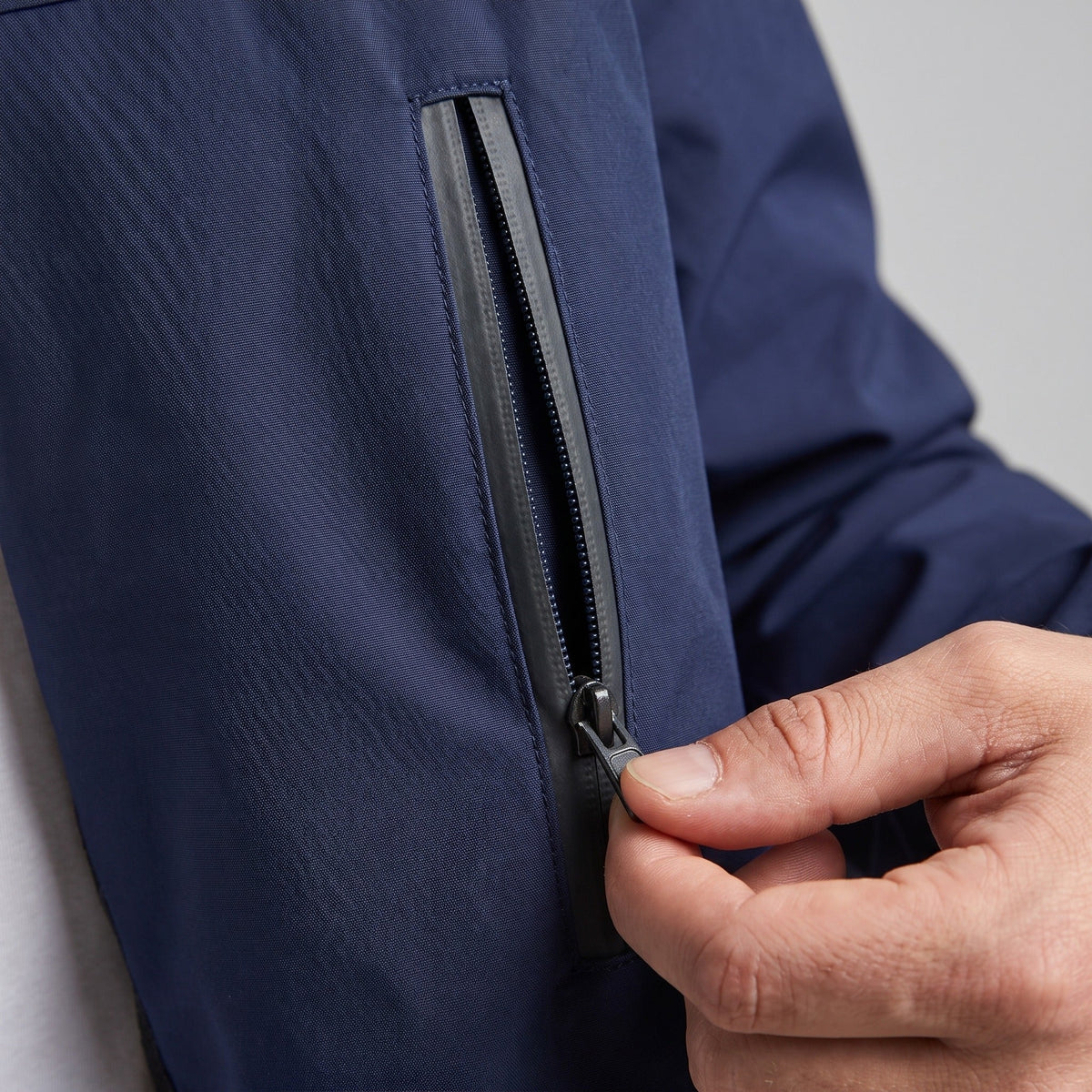 Close-up van donkerblauwe windbreaker met ritszak, gedragen door persoon | Boutique Moda
