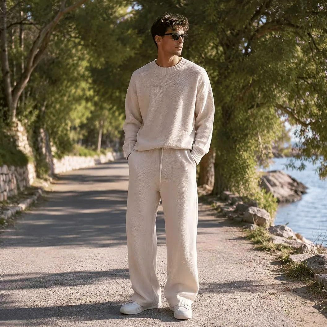 Man draagt crème gebreide oversized trui met wijde broek buiten | Boutique Moda