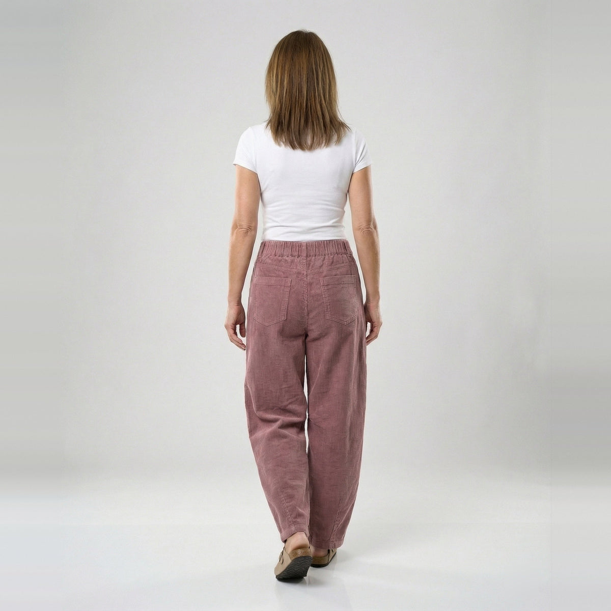 Vrouw draagt oudroze wijde corduroy broek met hoge taille, achteraanzicht | Boutique Moda