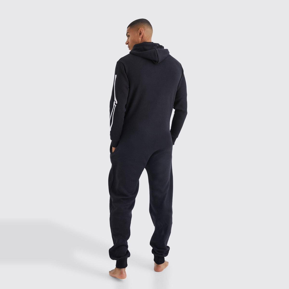 Zwarte onesie met capuchon, gedragen door man, van achteren gefotografeerd | Boutique Moda
