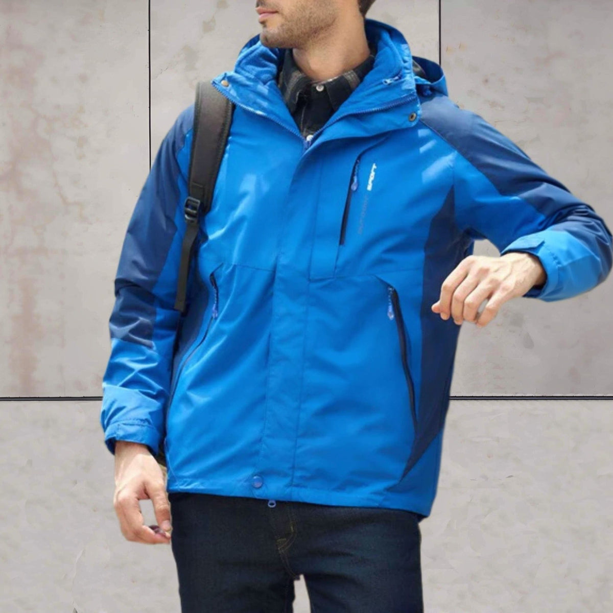 Blauwe wandeljas met capuchon, gedragen door man met rugzak buiten | Boutique Moda