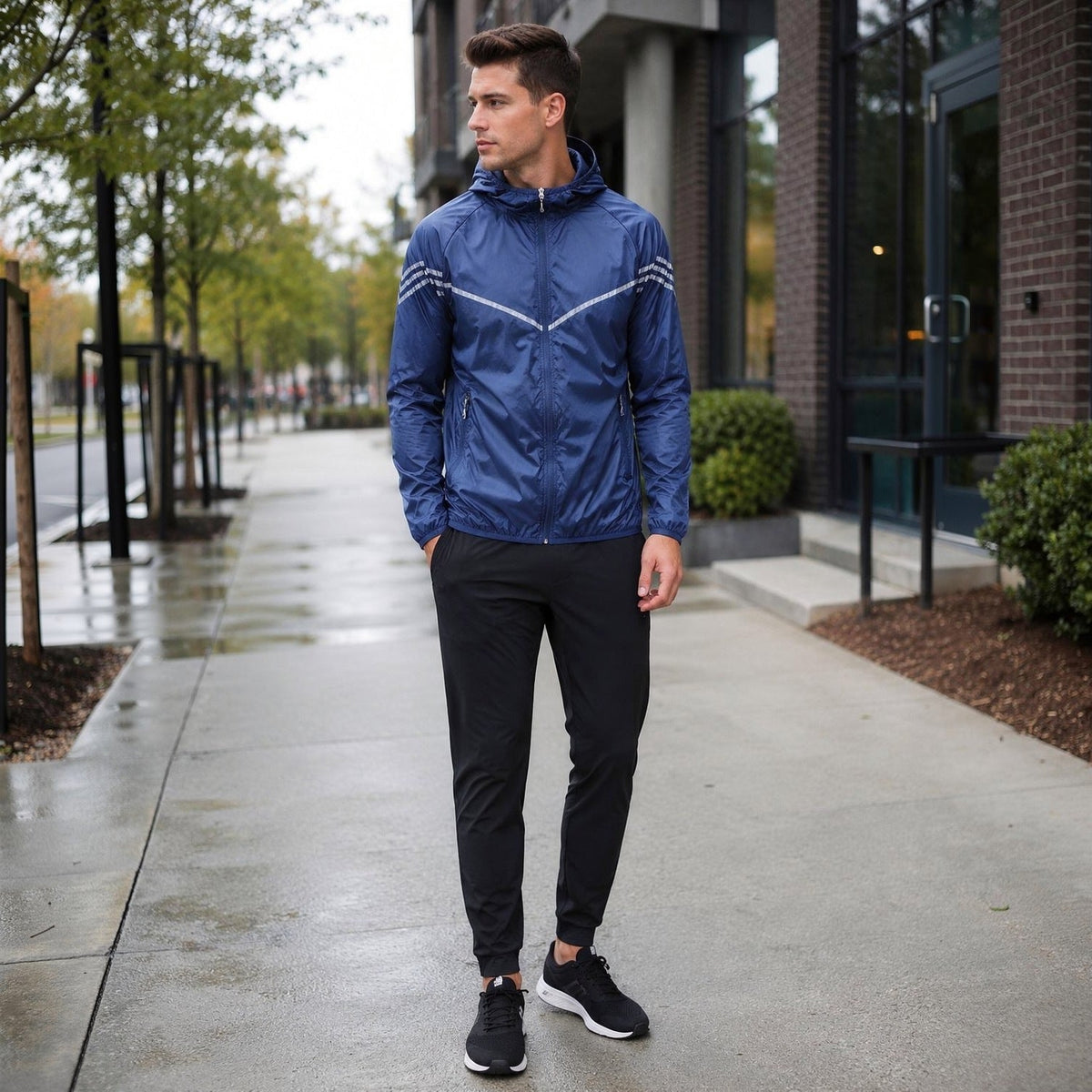 Blauwe waterdichte hardloopjas met capuchon, gedragen door man op straat | Boutique Moda