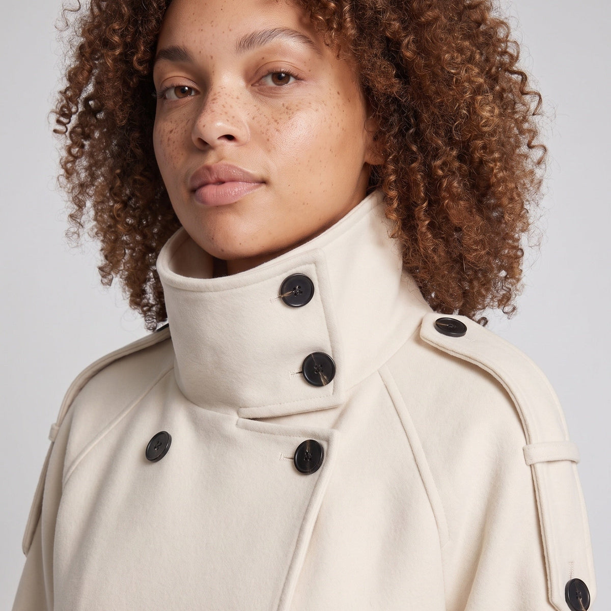 Ecru korte cape met opstaande kraag, gedragen door vrouw met krullend haar | Boutique Moda
