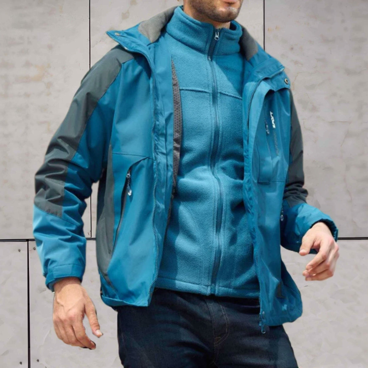 Man draagt blauwe 3-in-1 wandeljas met grijze fleece binnenjas, capuchon zichtbaar | Boutique Moda