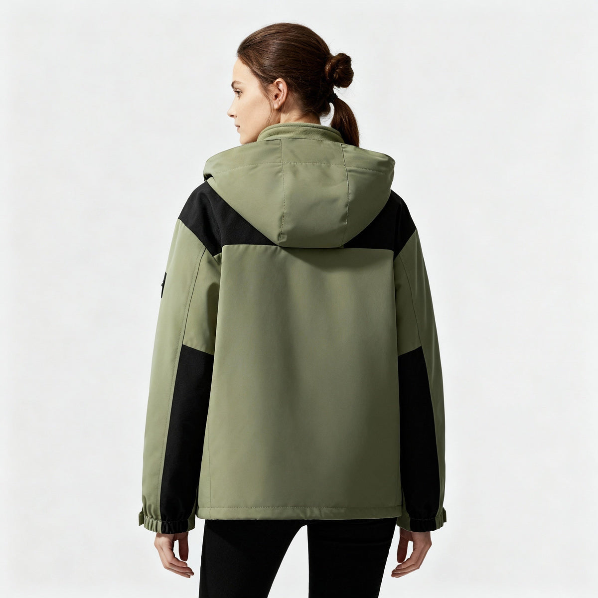 Groene jas met zwarte details en capuchon, gedragen door vrouw, achteraanzicht | Boutique Moda
