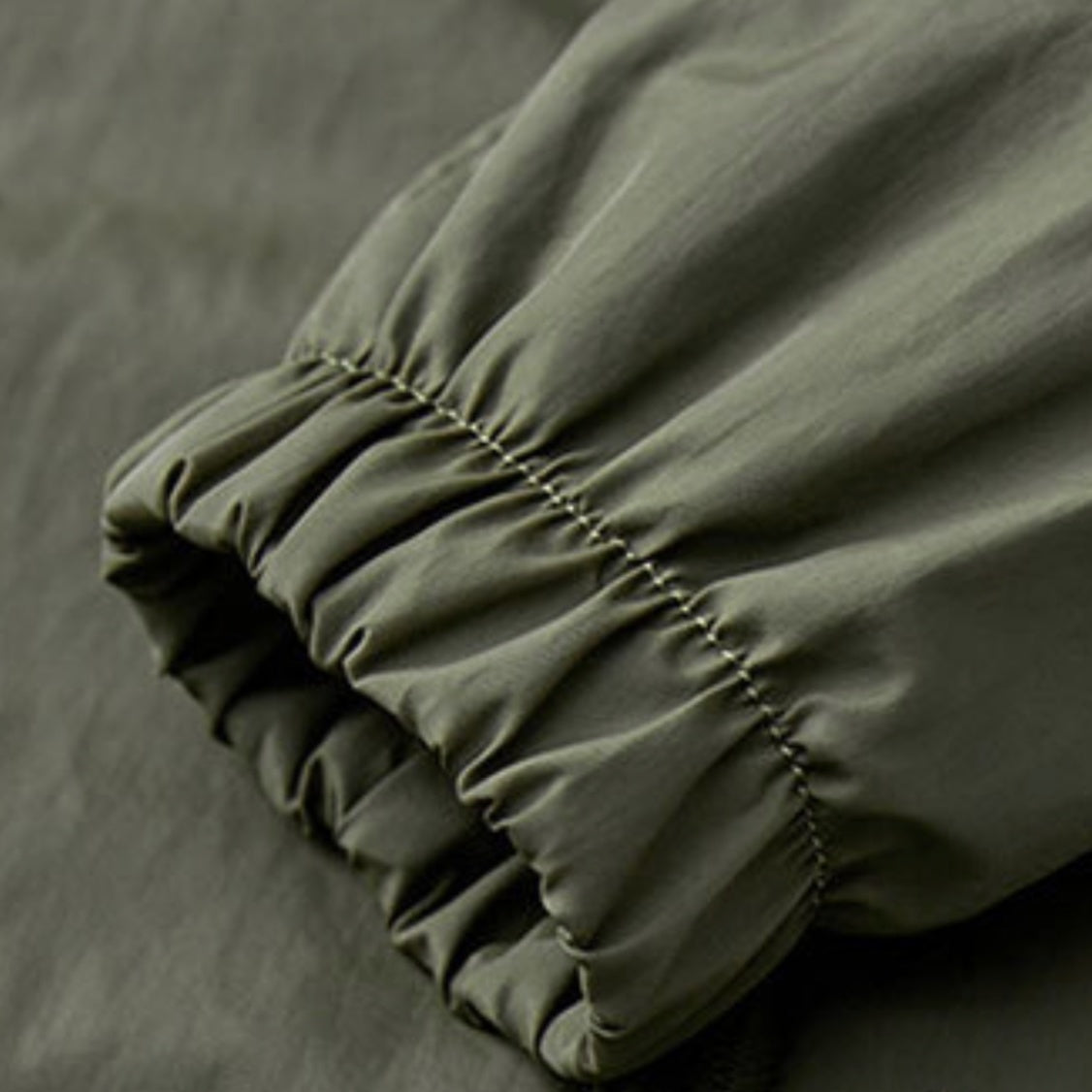 Close-up van legergroene mouw met elastische manchet en plooien | Boutique Moda