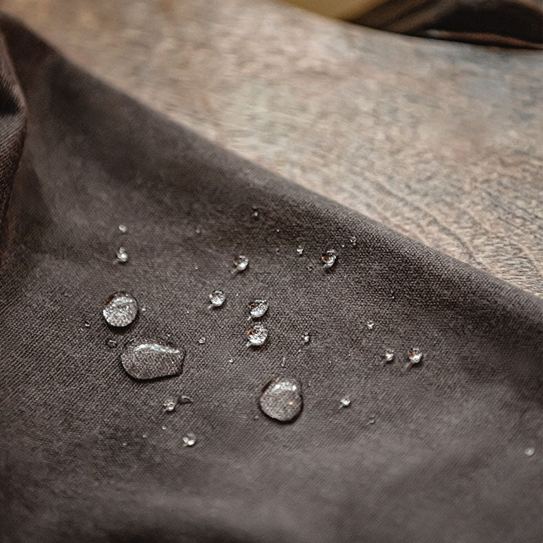 Waterdruppels op bruine gewaxte jas, close-up van waterafstotend oppervlak | Boutique Moda