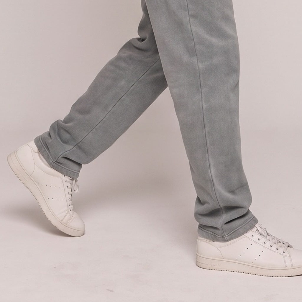 Grijze joggingbroek gedragen door persoon met witte sneakers, close-up beenpartij | Boutique Moda