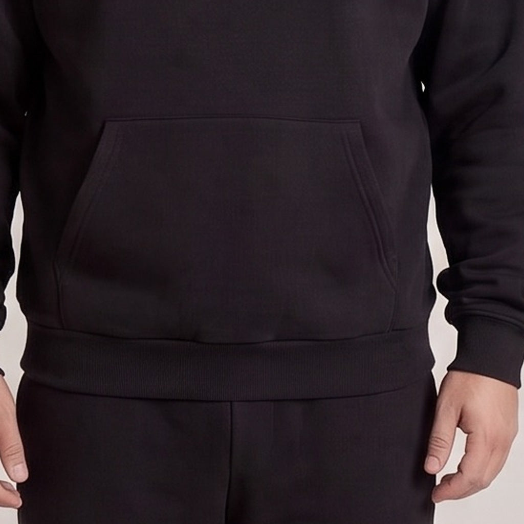 Zwarte hoodie met kangoeroezak, close-up gedragen door persoon, bijpassende joggingbroek zichtbaar | Boutique Moda