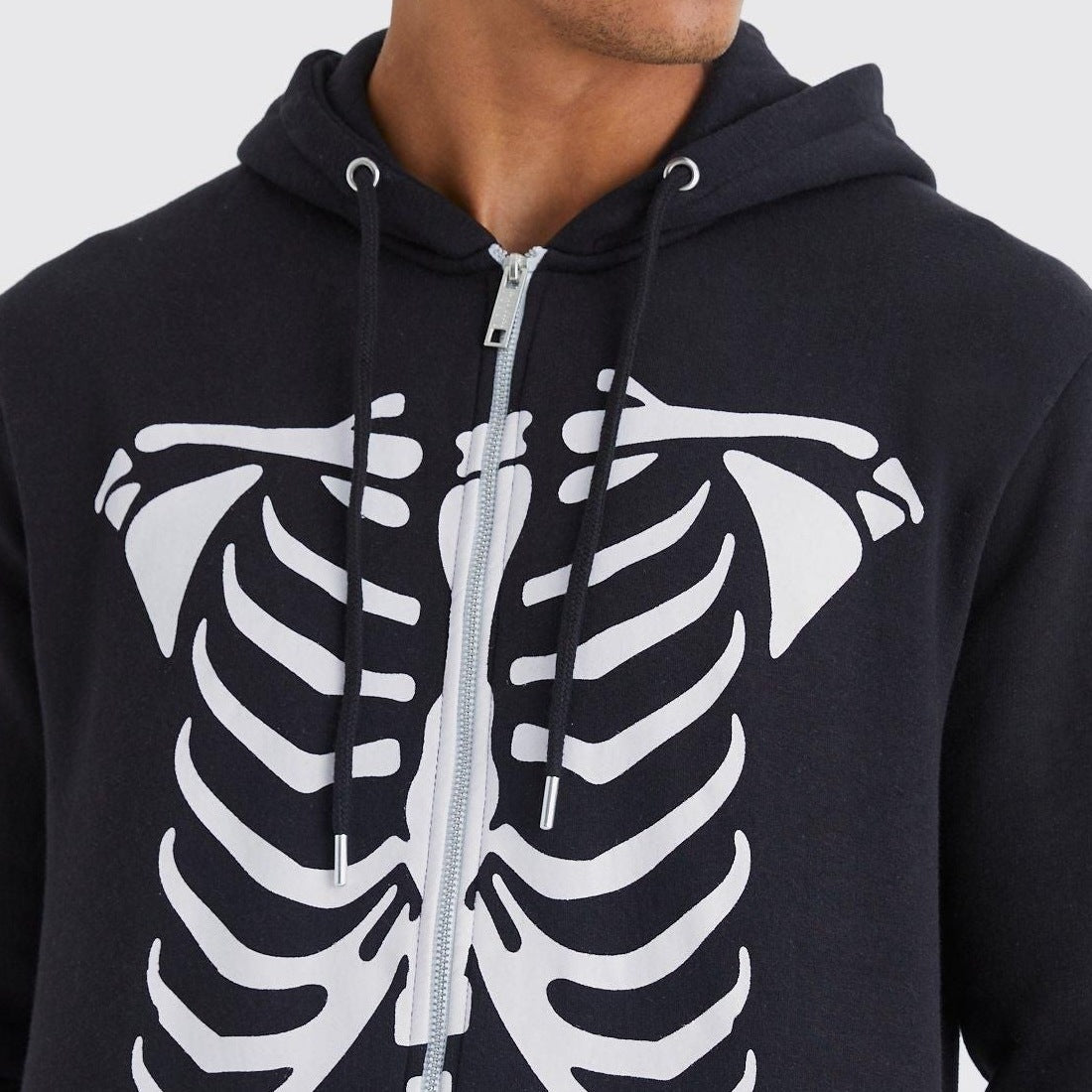 Zwarte hoodie met skeletprint en rits, gedragen door man, close-up torso | Boutique Moda