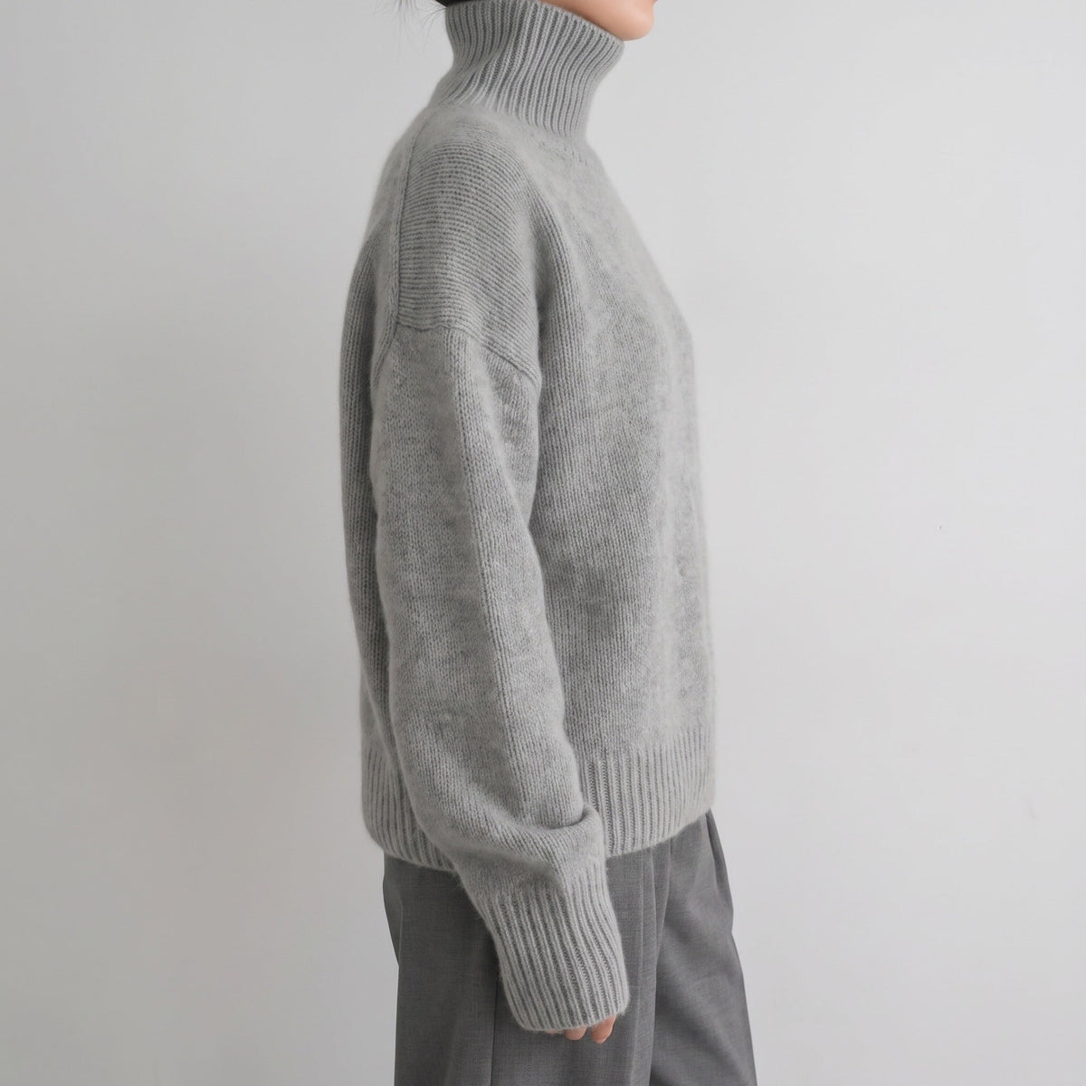 Grijze oversized coltrui, gedragen door persoon, zijaanzicht, gebreide structuur zichtbaar | Boutique Moda