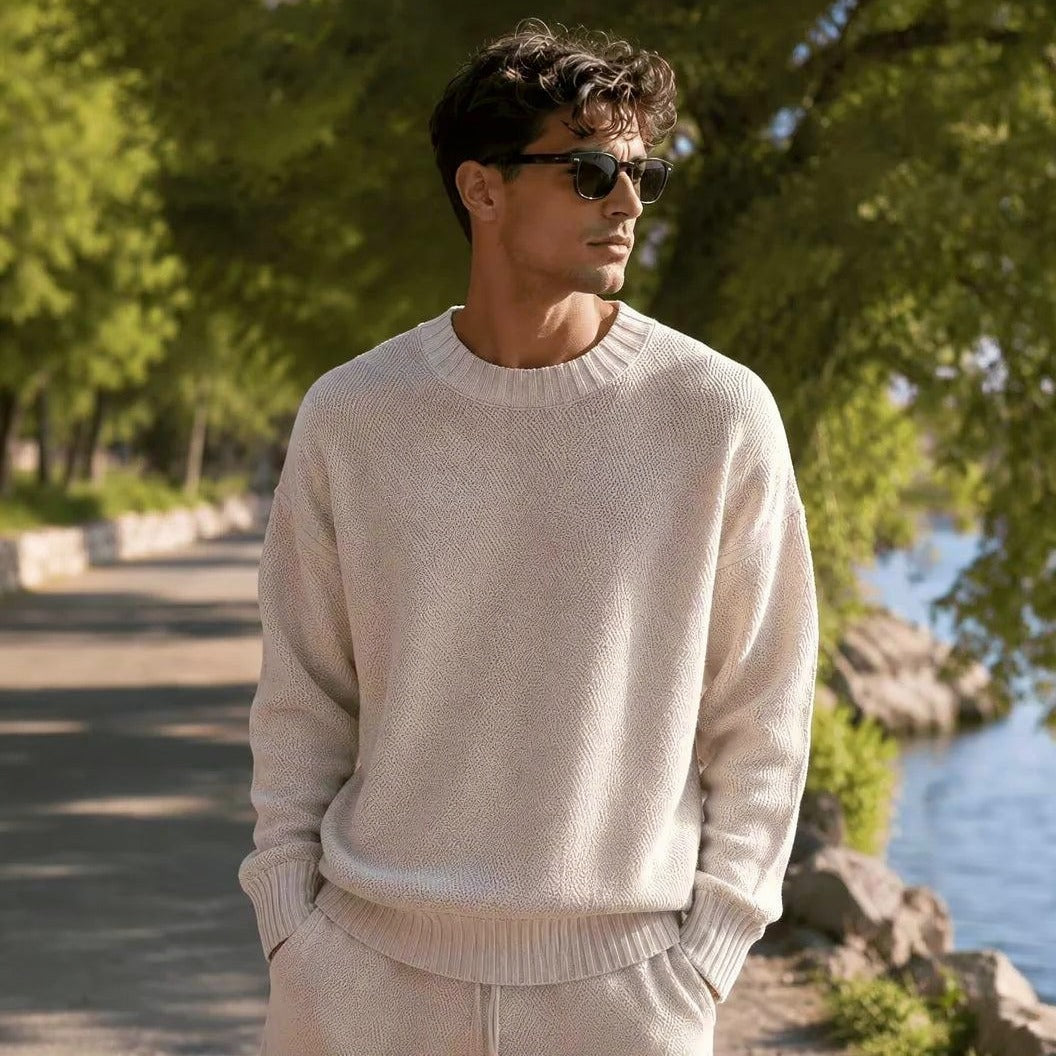 Man draagt crème gebreide trui met ronde hals, buiten bij water | Boutique Moda