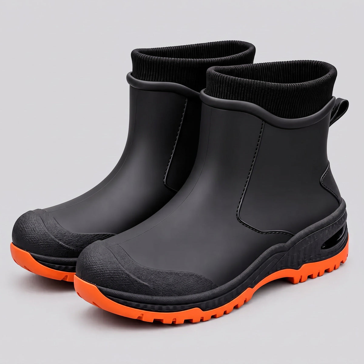 Zwarte enkelhoge regenlaarzen met oranje profielzool, los liggend getoond | Boutique Moda