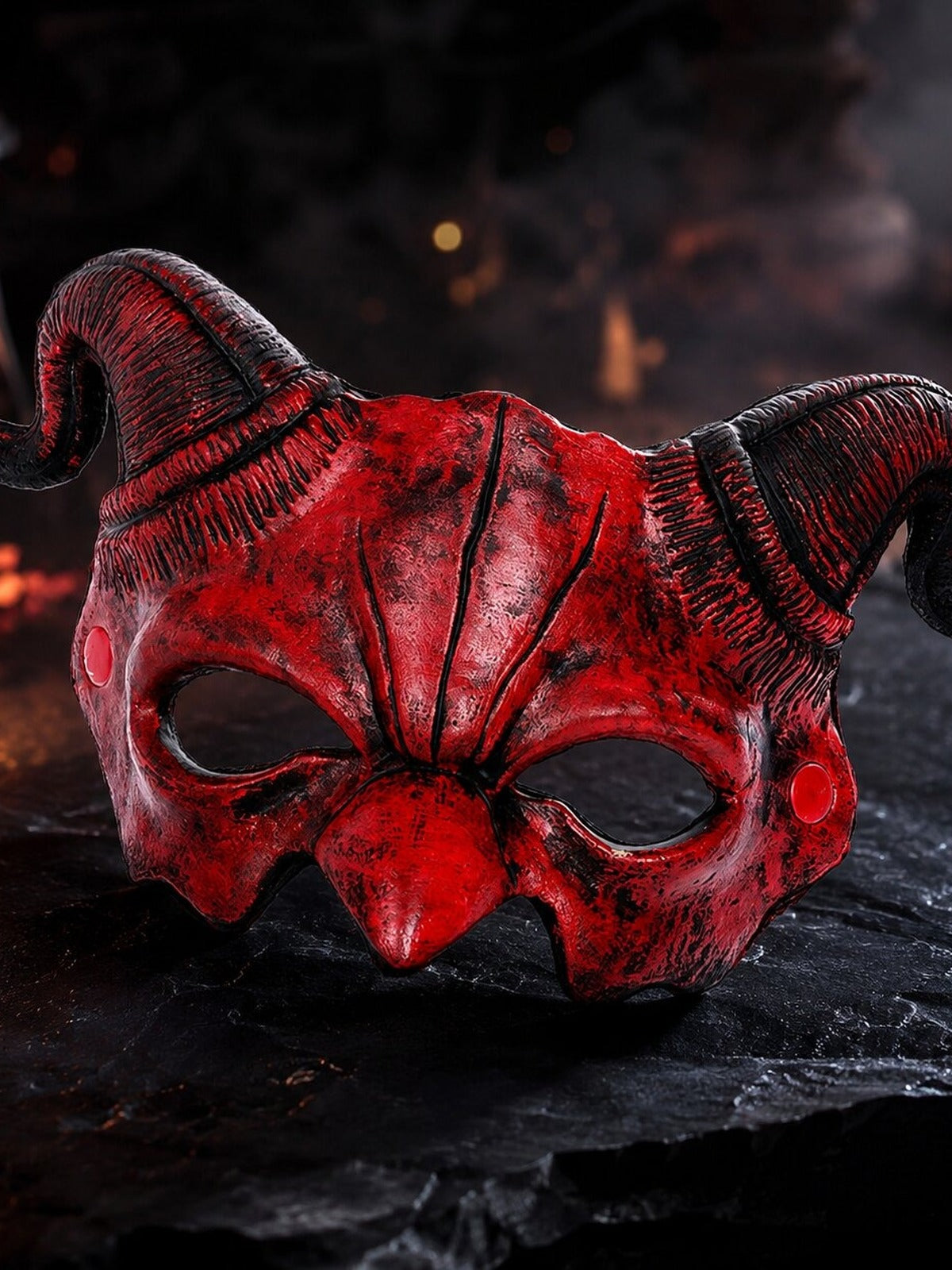 Rood demonenmasker met ramshoorns op een steen