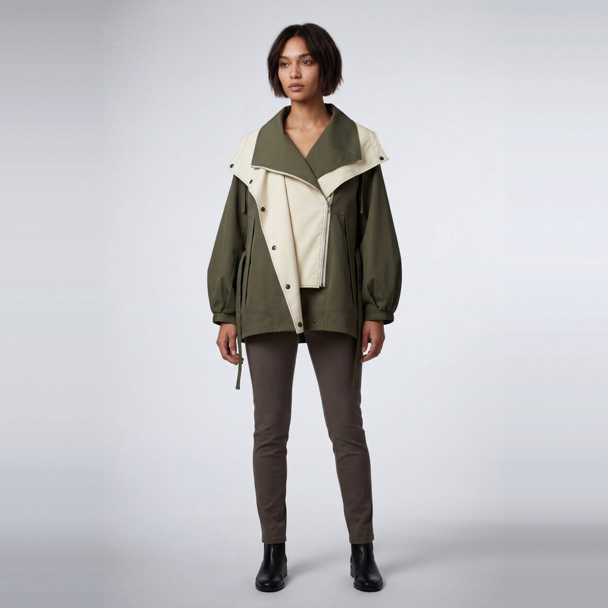 Groen-beige regenjas met capuchon gedragen door vrouw met bruine broek | Boutique Moda
