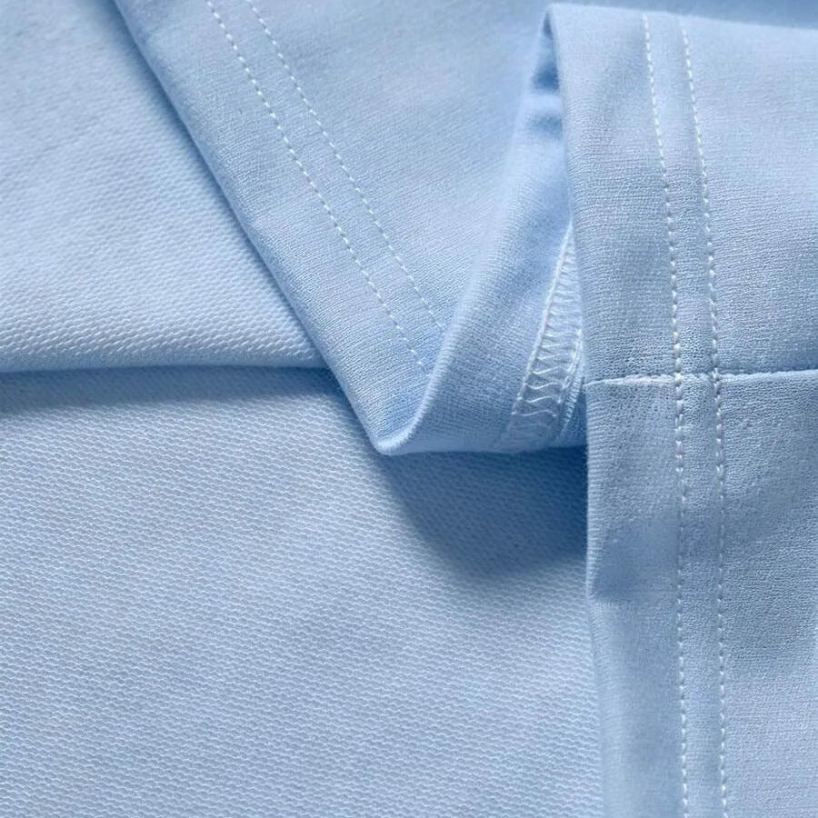 Lichtblauwe stof met zichtbare stiksels, close-up van gevouwen mouw | Boutique Moda