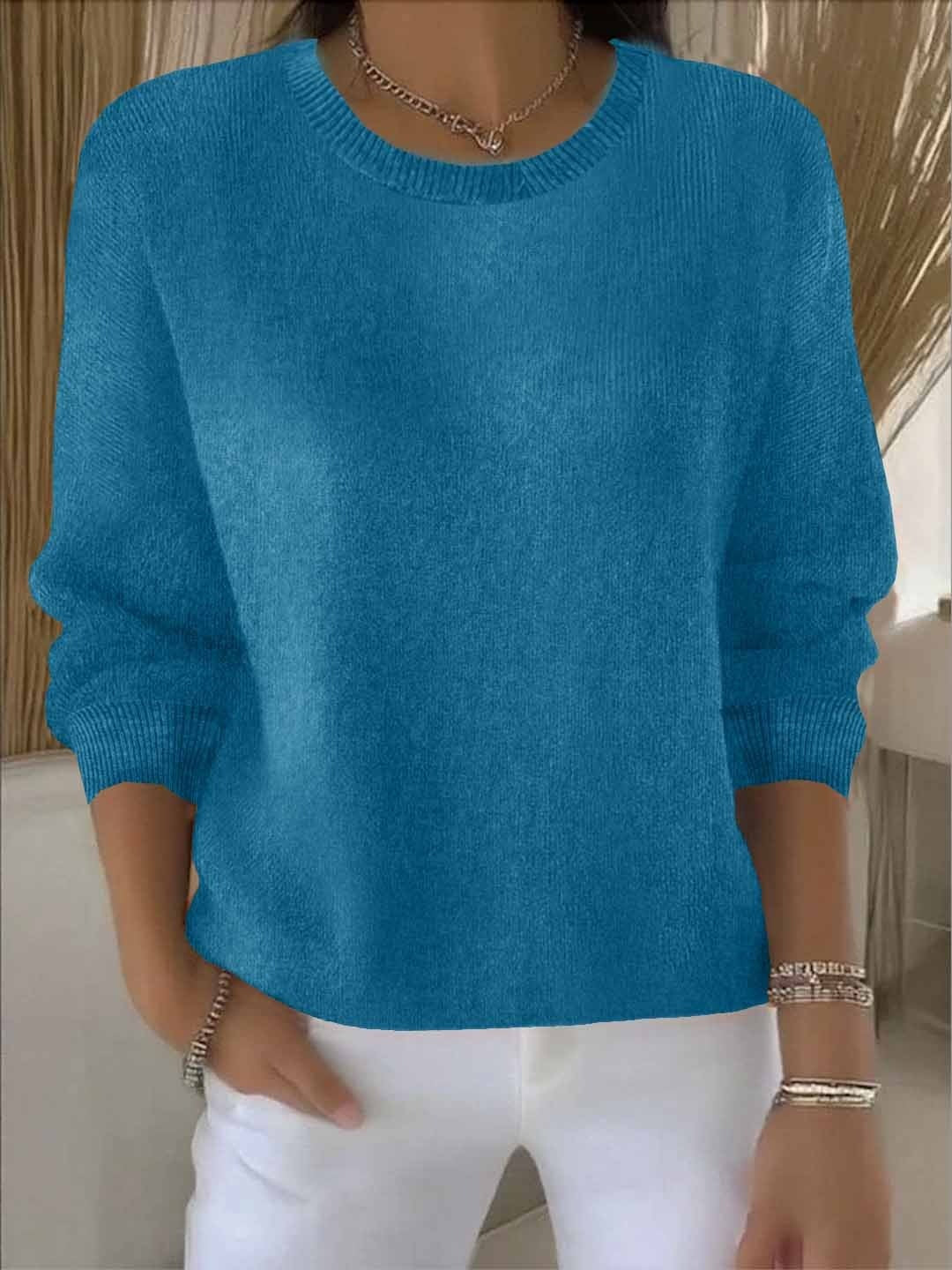 Fijngebreide oversized damestrui in petrolblauw met ronde hals, gedragen op een witte broek